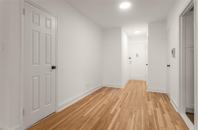 corridor with baseboards and light wood finished floors