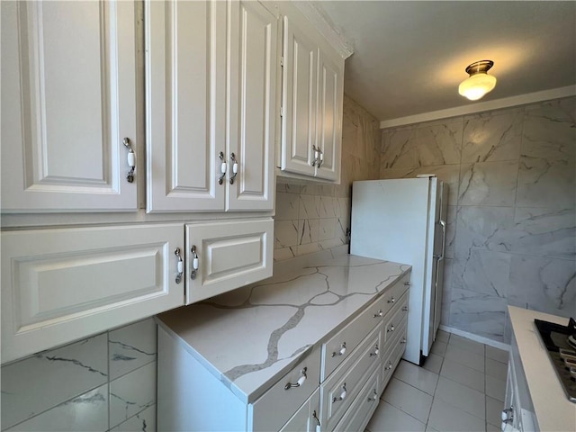 142 Garth Rd Unit 1P, Scarsdale, NY 10583 - kitchen featuring freestanding refrigerator, white cabinetry, light stone counters, and light tile patterned floors