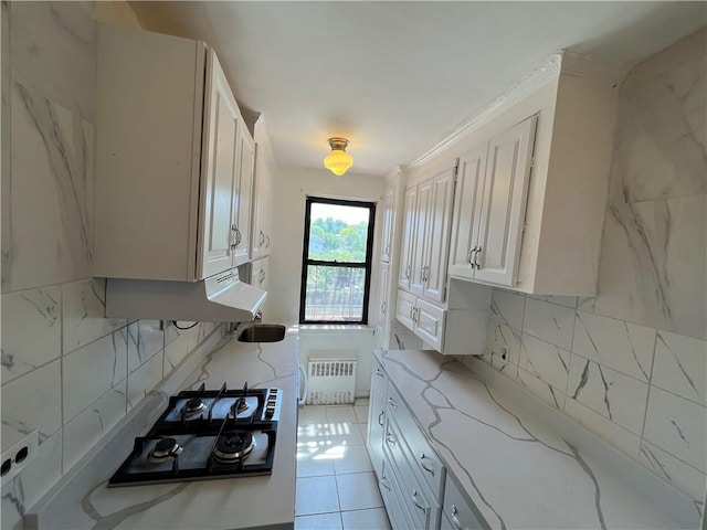142 Garth Rd Unit 1P, Scarsdale, NY 10583 - kitchen with radiator heating unit, stainless steel gas stovetop, decorative backsplash, light stone countertops, and ornamental molding