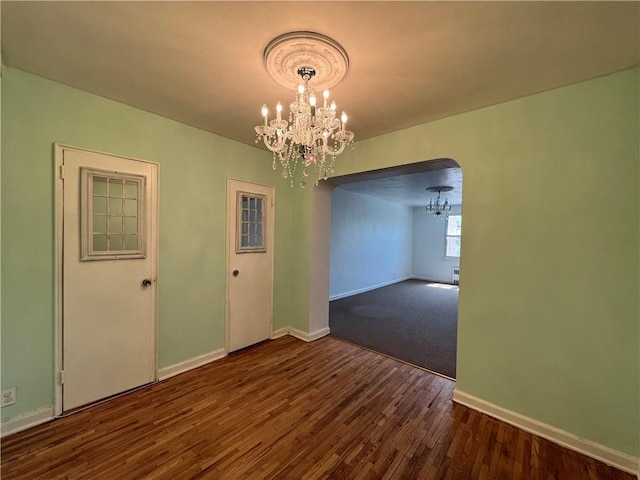 142 Garth Rd Unit 1P, Scarsdale, NY 10583 - unfurnished dining area with a chandelier, baseboards, wood finished floors, and arched walkways