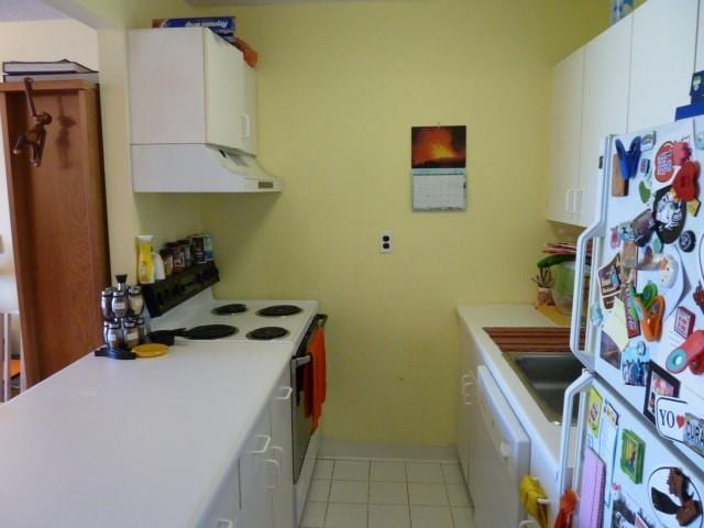 kitchen featuring light tile patterned floors, light countertops, white appliances, and white cabinets