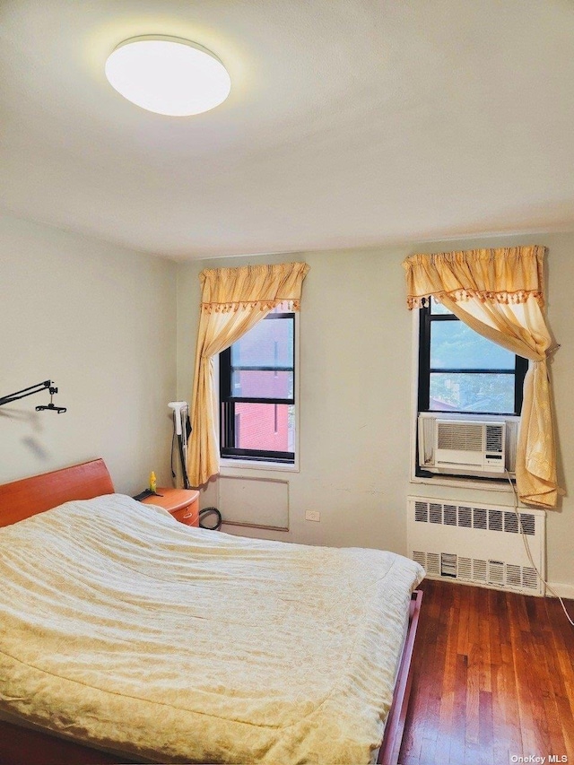 bedroom featuring dark wood-type flooring, cooling unit, and radiator heating unit