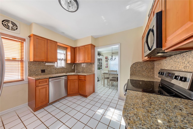 kitchen featuring appliances with stainless steel finishes, brown cabinetry, a sink, and visible vents