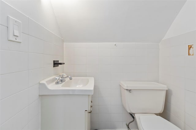 half bath with lofted ceiling, toilet, tile walls, and vanity