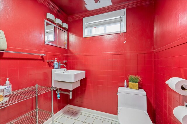 bathroom with toilet, tile patterned flooring, ornamental molding, and tile walls