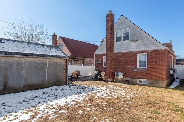 back of house with brick siding, a chimney, and fence