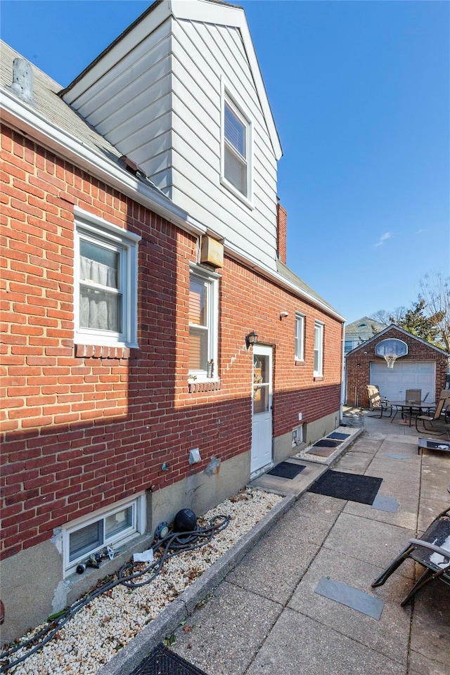 view of side of property with brick siding and an outdoor structure