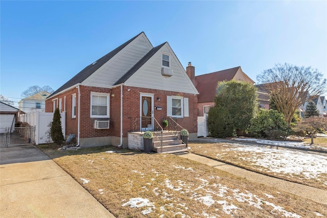 view of front of property with a gate, brick siding, fence, and a chimney