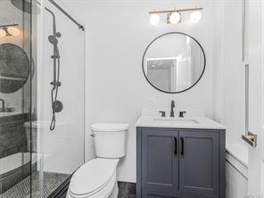 bathroom with a stall shower, vanity, and toilet