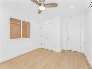 spare room featuring light wood finished floors, baseboards, a ceiling fan, a wall mounted AC, and recessed lighting