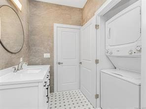 laundry room featuring stacked washer and dryer and a sink