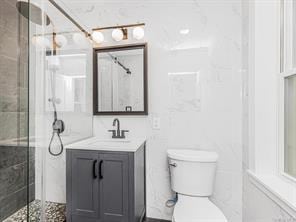 full bathroom with tiled shower, vanity, and toilet