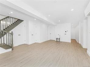 unfurnished living room featuring stairway, a wall mounted AC, wood finished floors, and recessed lighting