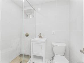 full bathroom featuring a stall shower, a sink, and toilet