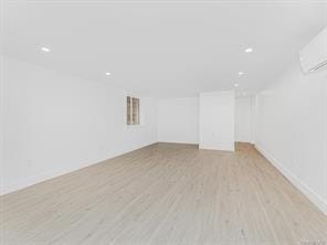 empty room with light wood-style floors, recessed lighting, and an AC wall unit