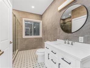 bathroom with toilet, recessed lighting, vanity, tile walls, and a stall shower