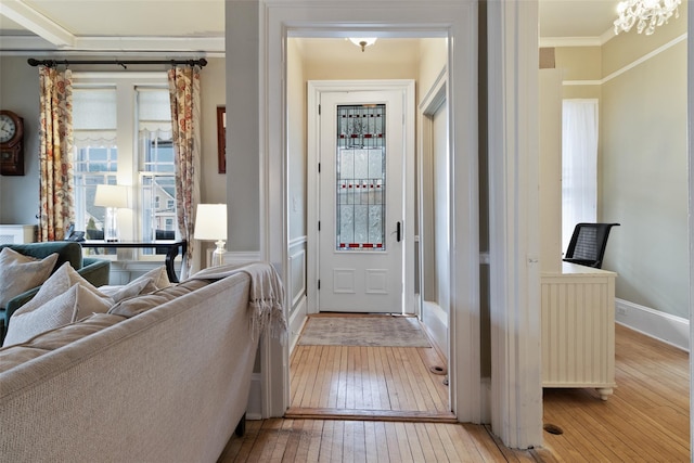 entrance foyer with light wood finished floors, a chandelier, crown molding, and baseboards