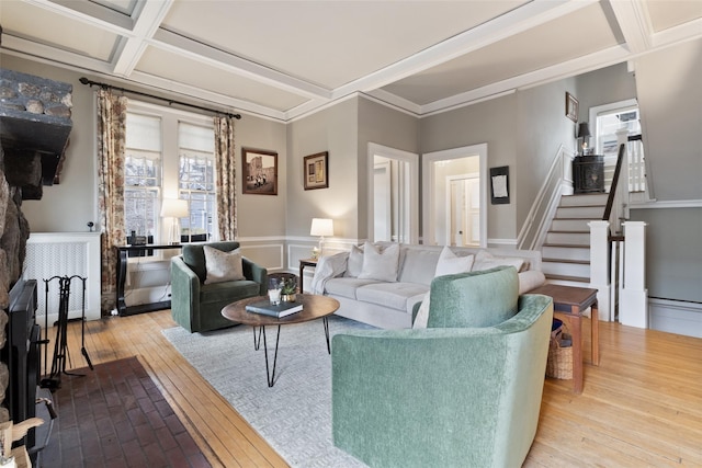 living area featuring beamed ceiling, coffered ceiling, hardwood / wood-style floors, crown molding, and stairs