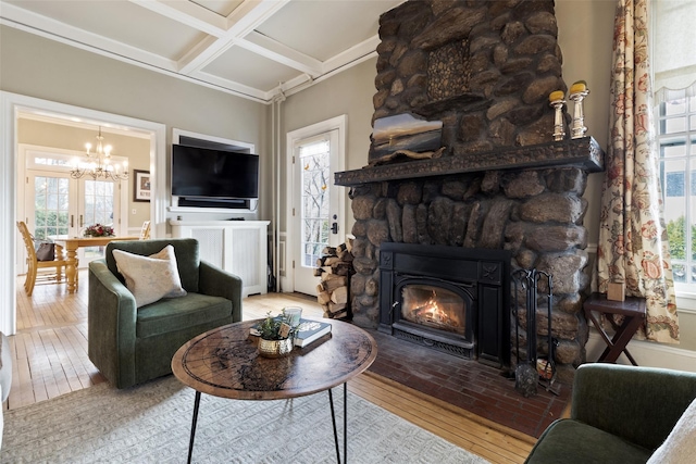 living area with a chandelier, beamed ceiling, a fireplace, coffered ceiling, and wood-type flooring