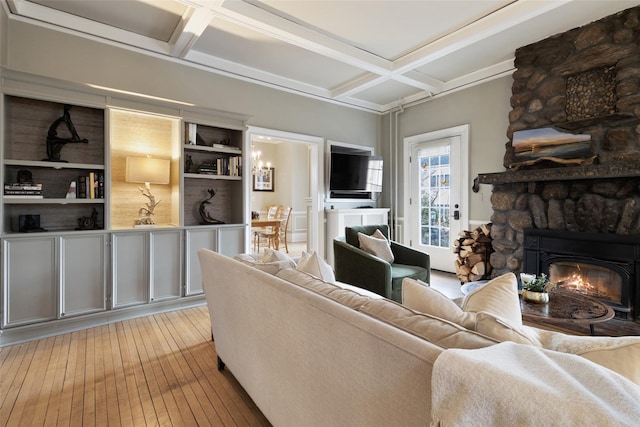 living area featuring beam ceiling, coffered ceiling, a fireplace, and light wood finished floors