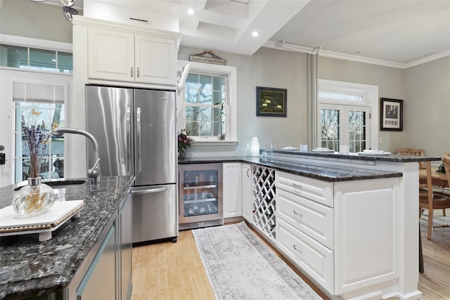 kitchen with wine cooler, light wood-type flooring, a wealth of natural light, a peninsula, and freestanding refrigerator