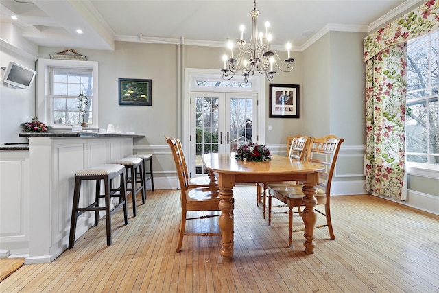 dining area with light wood-style flooring, french doors, and crown molding