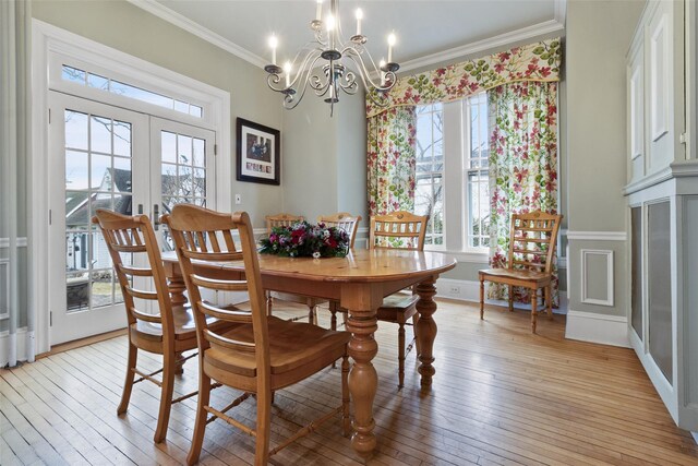 dining area with baseboards, light wood-style floors, french doors, crown molding, and a chandelier