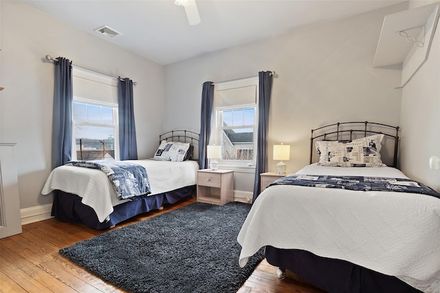 bedroom featuring visible vents, multiple windows, and hardwood / wood-style flooring