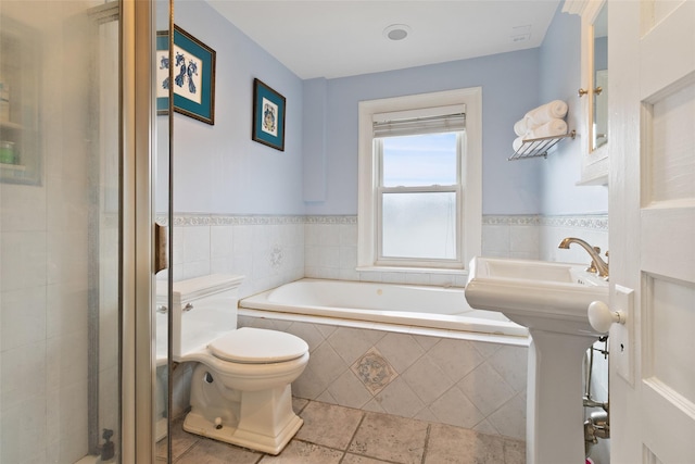 full bath with a bath, a stall shower, wainscoting, tile patterned floors, and toilet