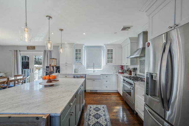 kitchen with visible vents, french doors, appliances with stainless steel finishes, wall chimney exhaust hood, and backsplash