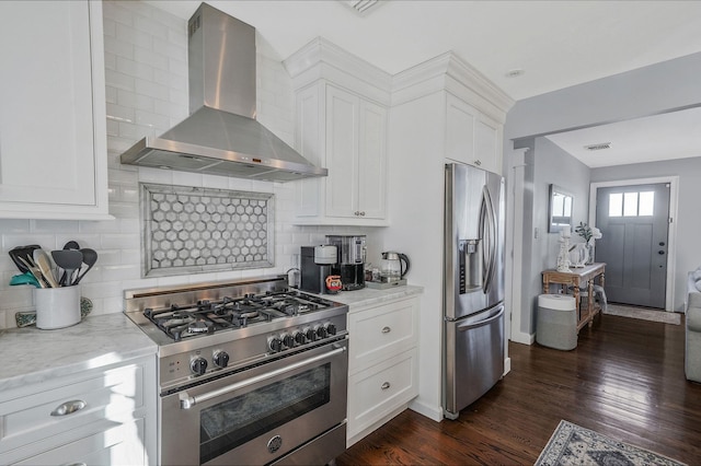 kitchen featuring dark wood finished floors, wall chimney range hood, white cabinetry, and appliances with stainless steel finishes