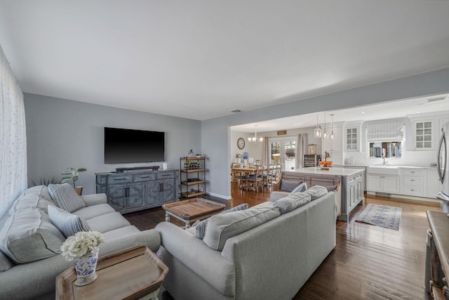 living room with a notable chandelier, dark wood-type flooring, and visible vents