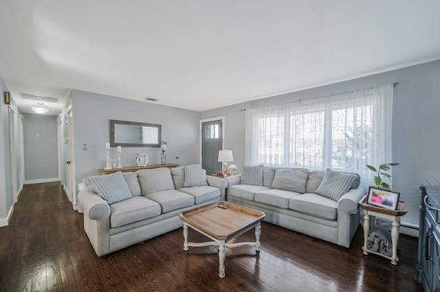 living room featuring wood finished floors, visible vents, and baseboards