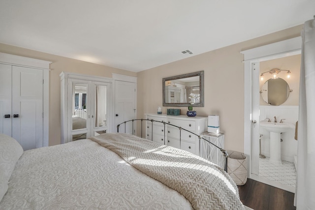 bedroom featuring visible vents, dark wood-type flooring, and connected bathroom