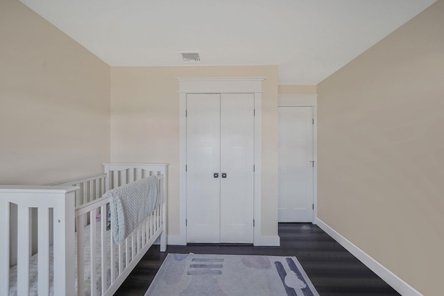 unfurnished bedroom featuring a closet, visible vents, baseboards, and wood finished floors