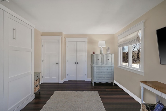 unfurnished bedroom featuring dark wood-style floors, baseboards, and a closet