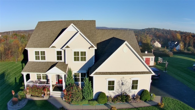 view of front of house featuring covered porch, a front yard, and roof with shingles