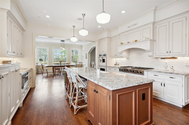 57 Old Orchard Ln, Scarsdale, NY 10583 - kitchen with dark wood-type flooring, tasteful backsplash, arched walkways, stainless steel gas cooktop, and light stone counters