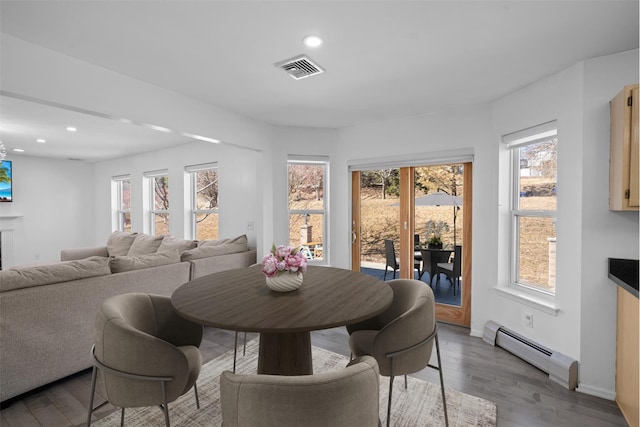 dining space with a baseboard heating unit, recessed lighting, visible vents, and wood finished floors