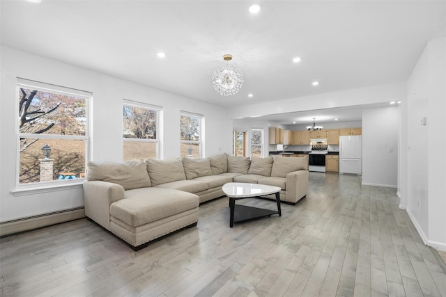 living area with a baseboard heating unit, light wood-type flooring, a notable chandelier, and recessed lighting