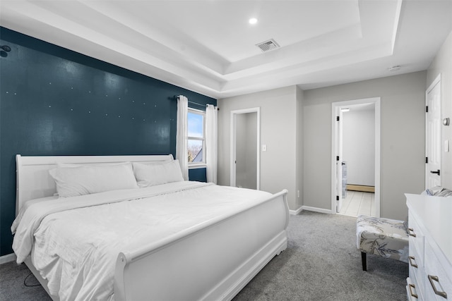 carpeted bedroom with a tray ceiling, visible vents, and baseboards