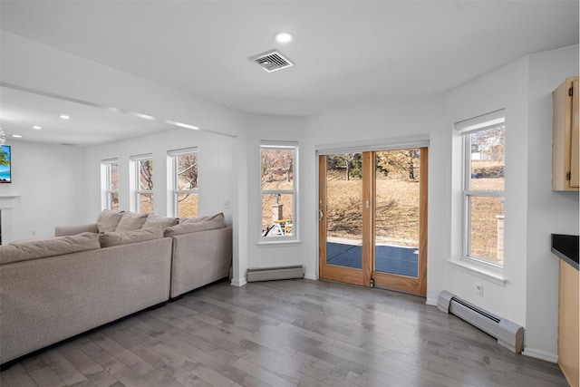 living room featuring baseboard heating, wood finished floors, visible vents, and recessed lighting