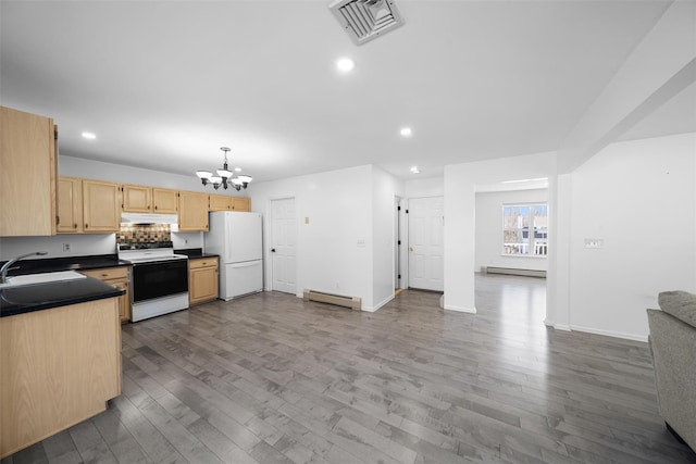 kitchen featuring under cabinet range hood, range with electric stovetop, visible vents, baseboard heating, and freestanding refrigerator