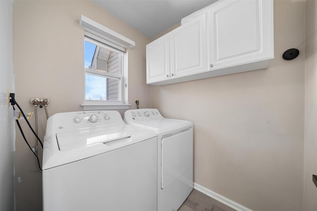 laundry room featuring baseboards, wood finished floors, cabinet space, and washer and dryer