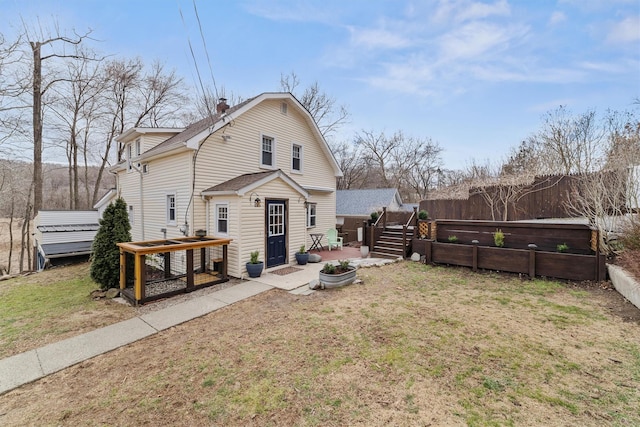 rear view of property featuring fence, a wooden deck, roof with shingles, a lawn, and a chimney