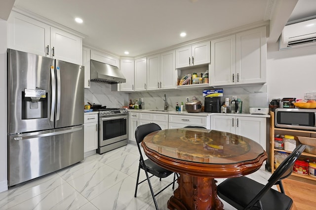 kitchen featuring a wall unit AC, wall chimney exhaust hood, appliances with stainless steel finishes, marble finish floor, and a sink