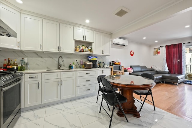 kitchen featuring marble finish floor, stainless steel appliances, an AC wall unit, light countertops, and a sink