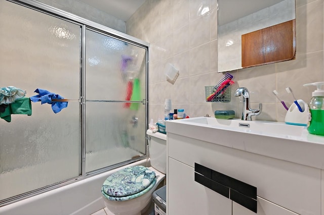 bathroom featuring tile walls, backsplash, toilet, combined bath / shower with glass door, and vanity