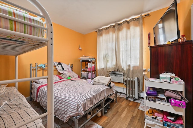 bedroom with a baseboard radiator and wood finished floors