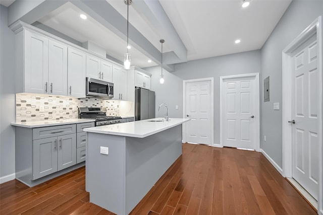 kitchen featuring dark wood finished floors, stainless steel appliances, backsplash, a sink, and an island with sink